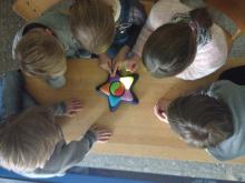 Kinder schauen von oben auf ein sternförmiges Tischspiel